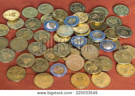Polish 2 PLN and 5 PLN golden commemorative coins on wooden table.