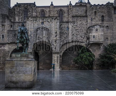 Single person on a rainy day in Ramon Berenguer Square and Royal palace in Barcelona city, Gothic quarter