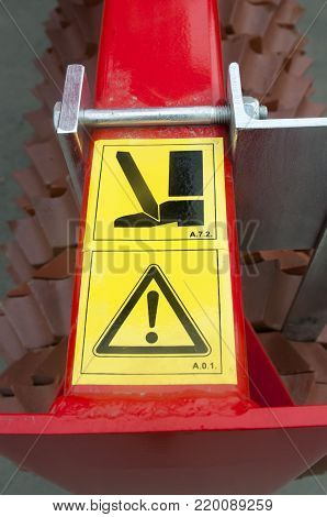 Warning sign on agricultural machinery. Caution when the reel drums are stopped, the blades rotate. Observe the distance. Do not shove hands and feet into the mechanism.