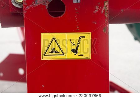 Warning sign on agricultural machinery. Before performing work under the inclined chamber and reel, it is necessary to fix the lifting cylinders with the help of the existing locking elements