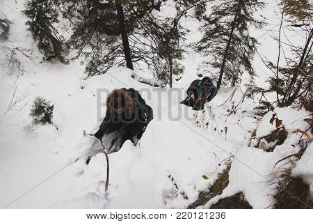 POLAND, TATRA MOUNTAINS, 03.11.2017,  A guy and a girl climb uphill on snow-covered rocks