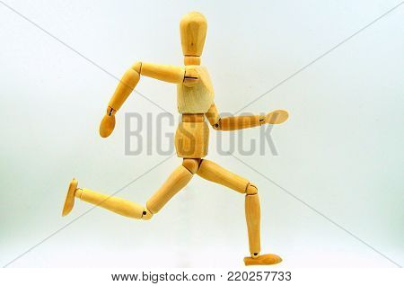 Wooden mannequin figure running against a white background.