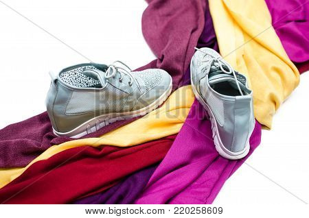 Stylish female sneakers shoes and colourful tippet scarf isolated on white background.