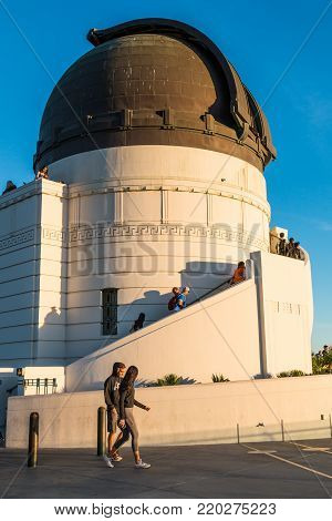 LOS ANGELES, CALIFORNIA - NOVEMBER 19, 2017:  People walk by the dome housing a Zeiss refracting telescope at Griffith Observatory, a popular destination with free nightly public telescope viewing.