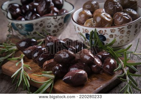 Cured, pickled or brined olive fruit on wooden table