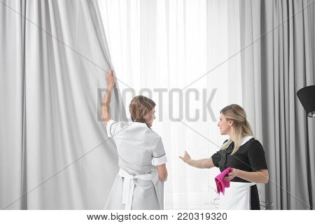Chambermaid in uniform teaching trainee indoors