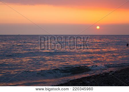 Sunset over the sea. The sun sets over the horizon. The sky over the sea bright red.
