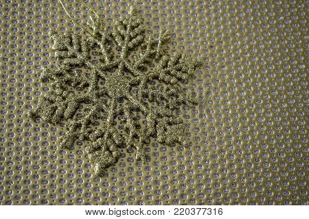 A gold decorative snowflake is set against a gold textured background.