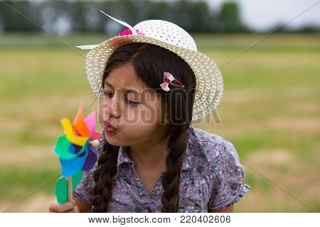 Smiling girl with strawhat and pinwheel in summer