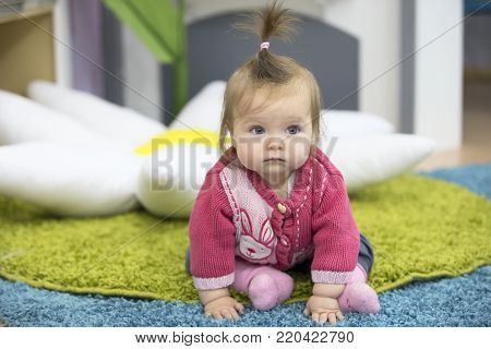 Belarus, Gomel, November 19, 2017. Six month old girl on the rug