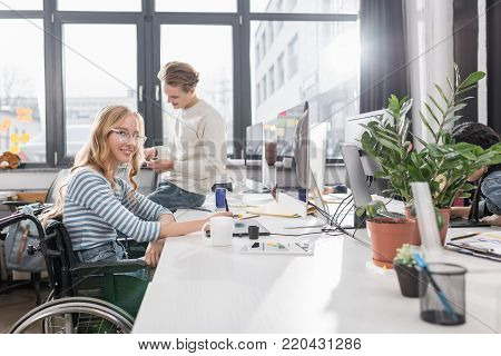 happy incapacitated person in wheelchair working at modern office