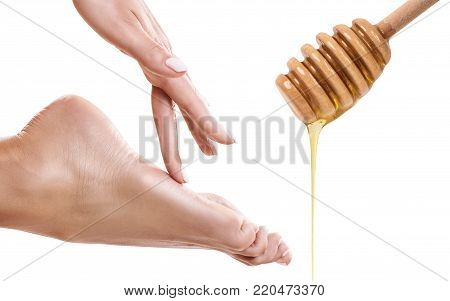 Honey flows down from spoon near female foot. Honey massage concept. Isolated on white.