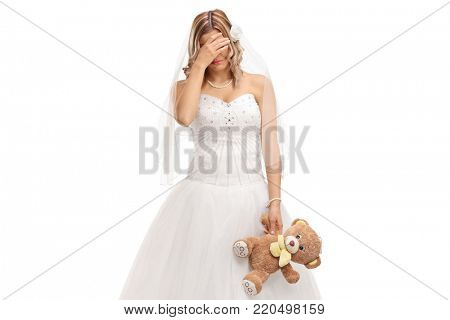 Sad young bride with a teddy bear crying isolated on white background