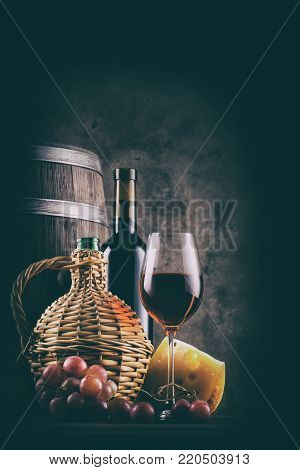 Wine still life with a barrel and red wine with grapes. Vintage toning.