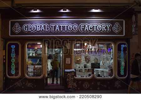 PALMA DE MALLORCA, BALEARIC ISLANDS, SPAIN - DECEMBER 5, 2017: Global Tattoo Factory on Sindicat shopping street with evening Christmas light decorations on December 5, 2017 in Palma de Mallorca, Balearic islands, Spain.