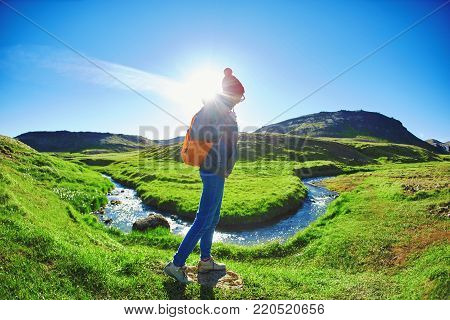woman traveler with small orange backpack on a walk in the Valley of the river of Hveragerdi Iceland. Hiking Tour of Reykjadalur Hot Springs