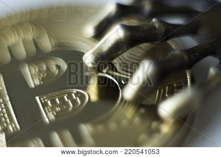 The concept of piracy with crypto currency. Metal fingers of the monster's paw on the front side of the golden bitcoin. Macro.