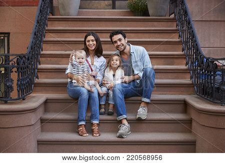 Young family with kids sitting on front stoops