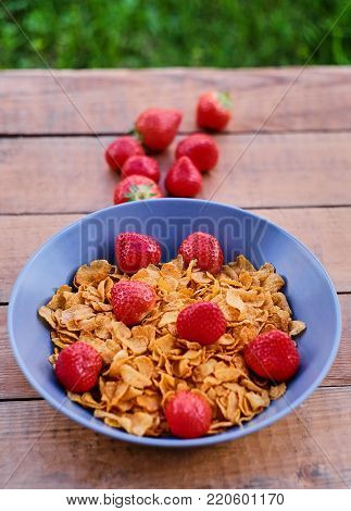 Delicious strawberry with corn flakes on a wooden desk.