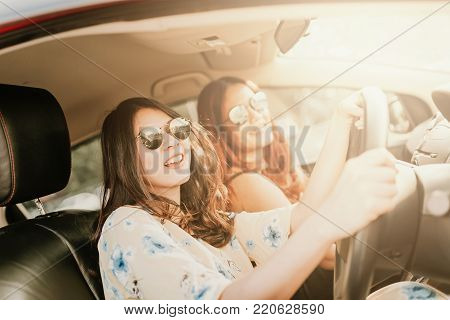 Young happy Asian girl best friends laughing and smiling in car during a road trip to vacation.