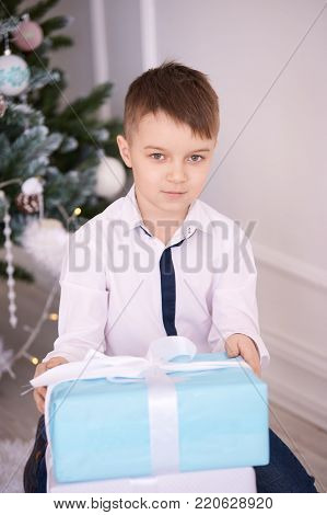 Little boy. Large gift boxes. Bright interior.