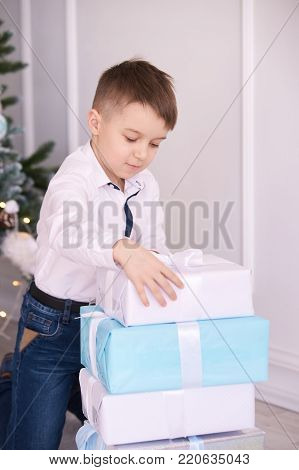 Little boy. Large gift boxes. Bright interior.
