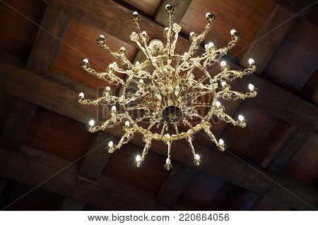 Golden antique chandelier under the ceiling of a restored castle
