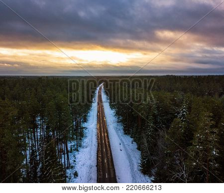 Aerial shot of snowy road in sunny winter evening