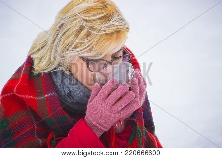Girl drinking hot tea in the winter forest, close up, horizontal format
