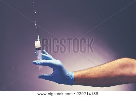 Man's hand in medical glove holds a syringe. Medical concept. Close up.