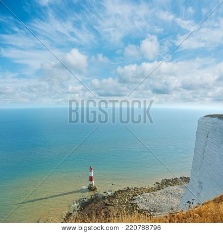 Aerial panoramic top view to famous red and white Beachy Head lighthouse and English Channel seascape with white chalk cliff of Beachy Head at the foreground and beautiful cloudy sky in the evening.