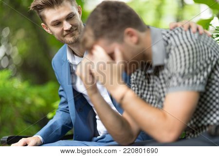 Man consoling sadness friend he closing his face, crying and feeling upset cause from his mistake in the park.Breakup concept
