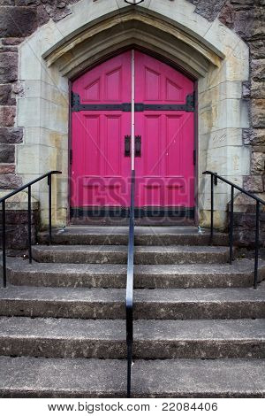Scalini che portano le doppie porte fucsia di una Chiesa cattolica con una caratteristica pietra triangolo