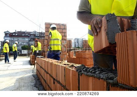 Construction worker putting brick on the wall