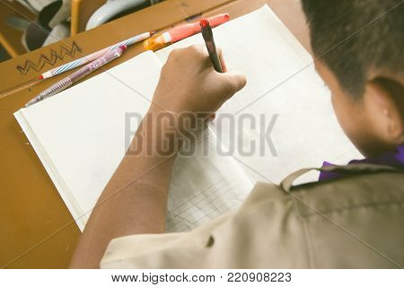 a very young student boy makes his exercise. Thai school in a small village