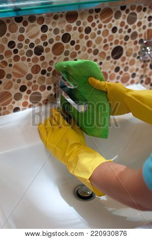 Closeup of woman housewife doing cleaning in the bathroom and wiping sink with rag