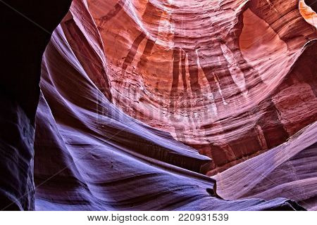 A Canyon Beneath the Surface--Waterstains paint the surface of orange standstone contrasted by smooth purple and shadowed rock in a slot canyon in Arizona. High contrast. Suitable for the travel industry, business offices, and hotel lobbies