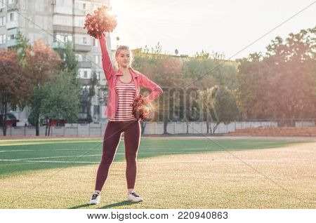 Girl In Pink Sport Suit With Pompoms Doing Splits At The Stadium.