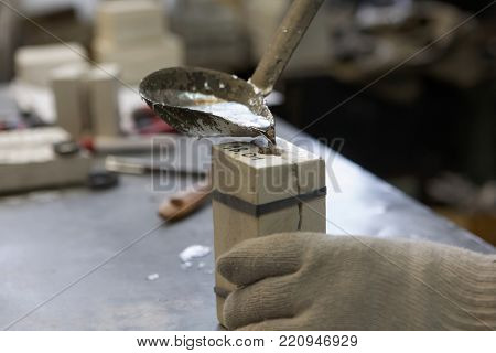 ST. PETERSBURG, RUSSIA - FEBRUARY 21, 2017: Worker pours molten tin into the casting form during the production of tin soldiers in the Niena studio. The enterprise was created in 1992