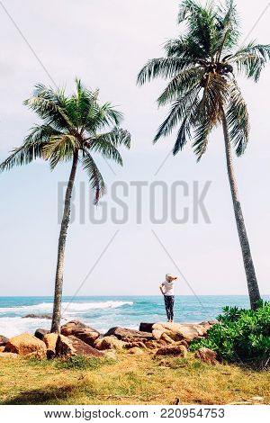 Woman stands at the ocean coast and looks on horizont line