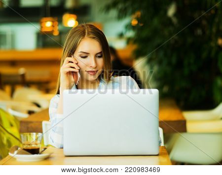 Business wooman using laptop at cafe. Young beautiful girl sitti