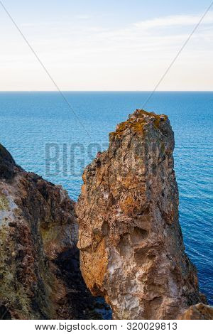 Exotic cliff rock, background sea 

Light brown color rocks and cliff, waves hitting the rocks