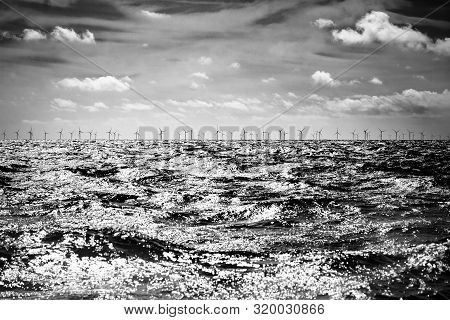 Offshore Wind Farm On Horizon With Cloud And Waves