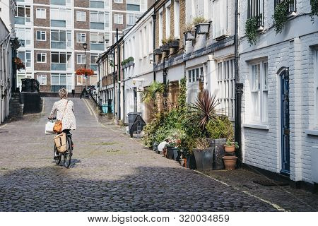 London, Uk - July 18, 2019: Rear View Of Woman Cycling Past Mews Houses In Paddington, London. House