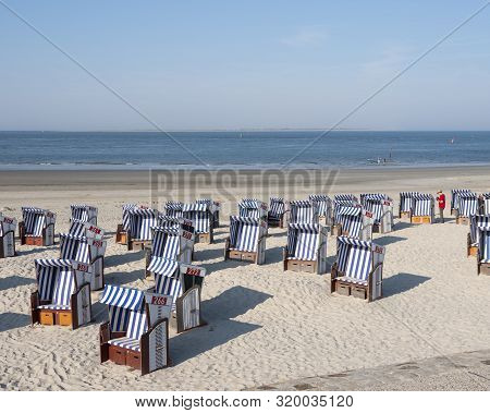 Norderney, Germany, 25 August 2019: Man In Red Shirt Checks Beach Korbs On The Island Of Norderney I