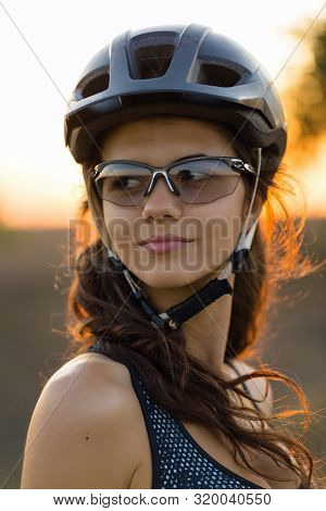 Girl On A Mountain Bike On Offroad, Beautiful Portrait Of A Cyclist At Sunset, Fitness Girl Rides A 