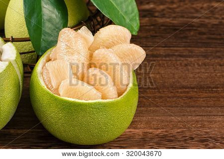 Fresh Peeled Pomelo, Grapefruit, Shaddock With Green Leaves On Dark Wooden Plank Table. Seasonal Fru