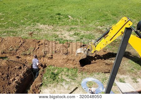 The Excavator Digs A Trench To Lay The Electric Cable.
