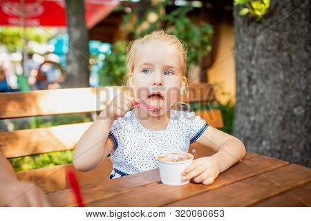 Adorable Blonde 3 Years Olg Eating Ice Cream In The Cafe Outside. Happy Childhood