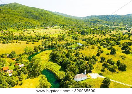 Croatia, Countryside Landscape, Small Stone Church By Gacka River In Region Of Lika, Aerial View